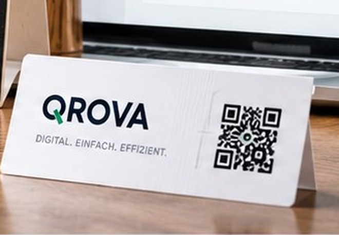QROVA-Tischaufsteller mit QR-Code neben einem Notebook